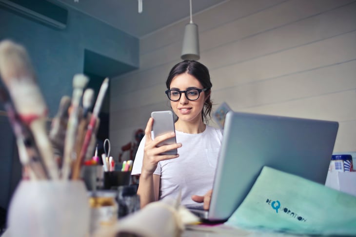 Woman looking at something on her phone at her desk