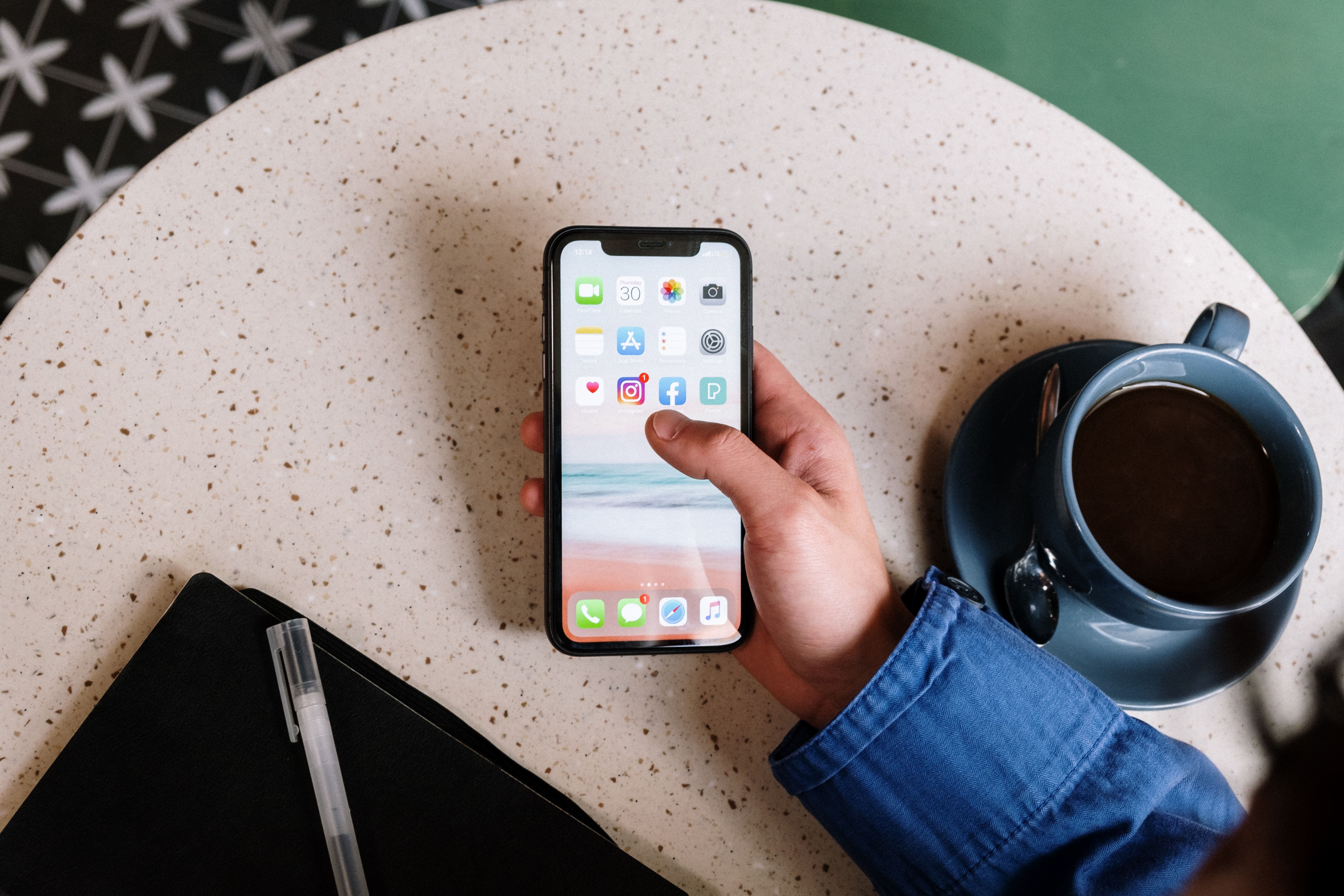 Someone scrolling on their smartphone at a coffee shop